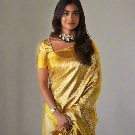 Woman wearing a gold saree with a decorative background